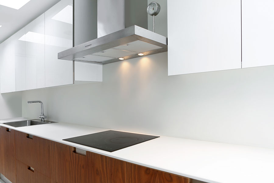 Bänkskiva av laminat i modernt kök med vita köksluckor och köksskåp av trä.