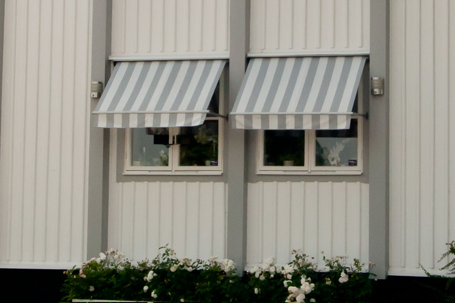 Markiser till fönster monterade på fasaden till en villa i en svensk småstad.