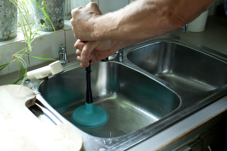 Använder vaskrensare med sugkopp i vasken för att trycka bort stopp