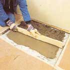 Fyll hålet med betong, jämna till och dra av överflödet med en rak bräda.