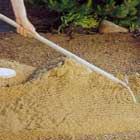 Drar ut sanden med en kratta
