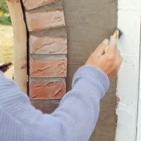 Jämna till alla kanter intill husväggen och tegelstensraden med en liten torr pensel.