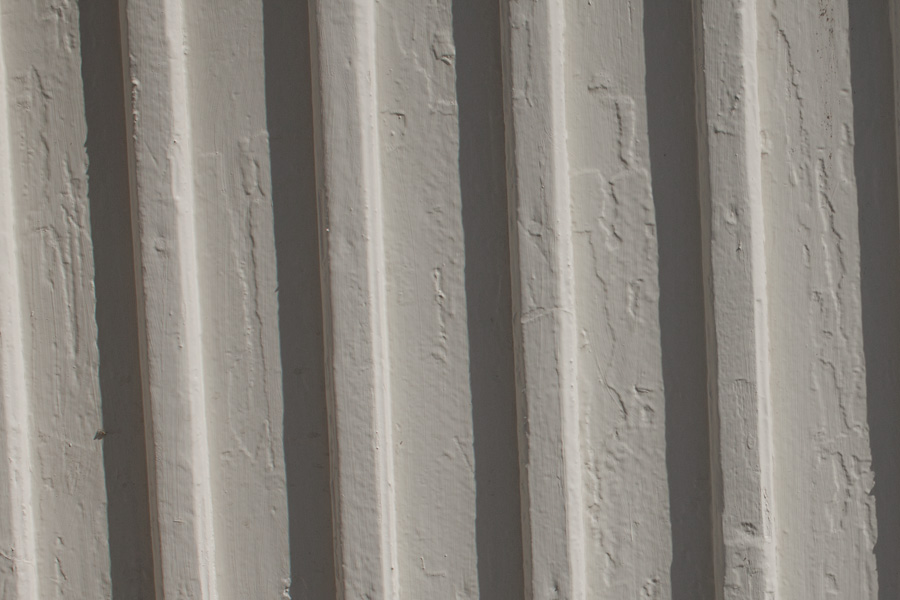 Bilden visar en närbild på en ommålad fasad med tydliga färgkanter som är ojämn på grund av att utesluten slipning med sandpapper.