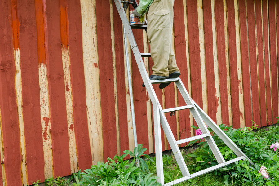 Bilden visar ett exempel på en stege med stegbreddare för att arbeta säkrare vid ett målningsarbete på fasader.