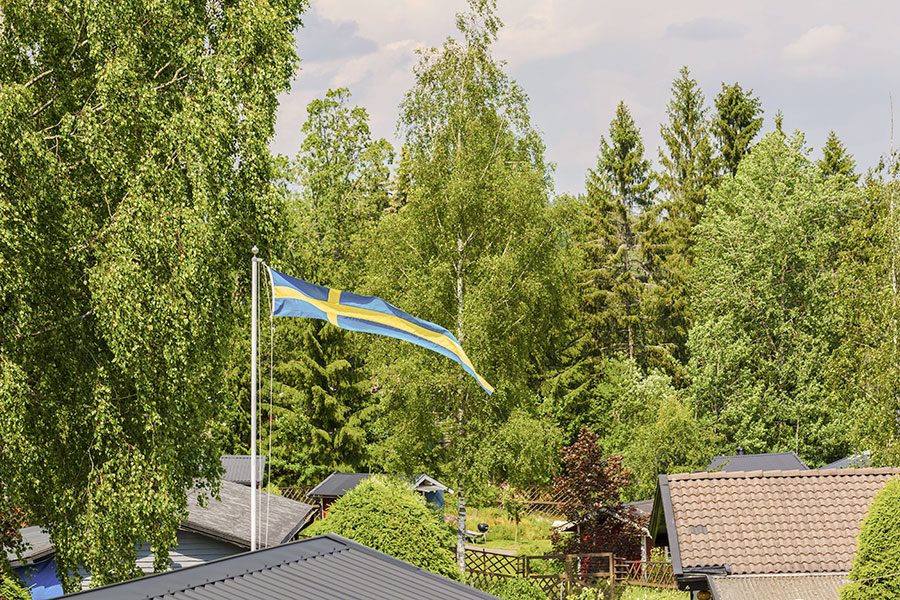 Flaggstång med svenska flaggan i villaträdgård