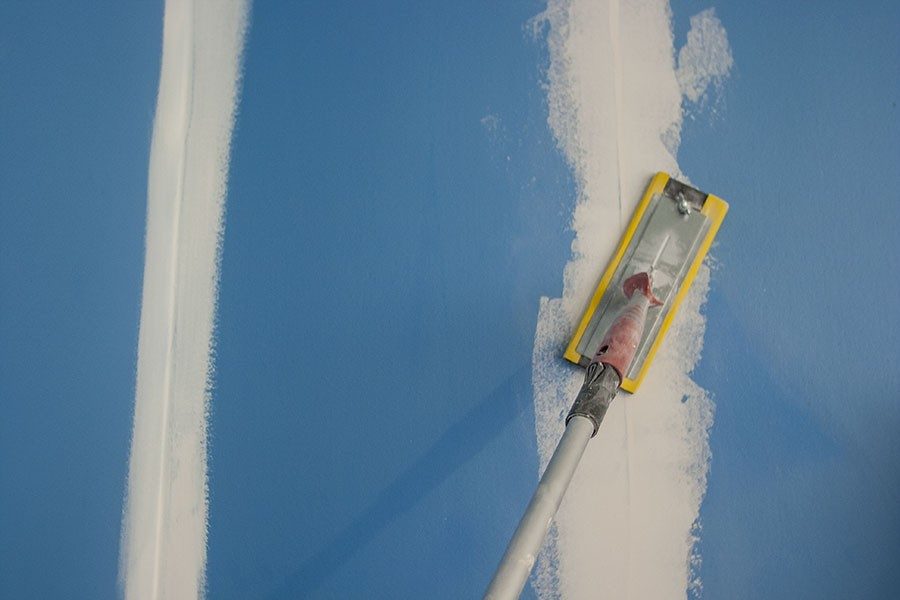 Slipning av spackel på vägg innan målning